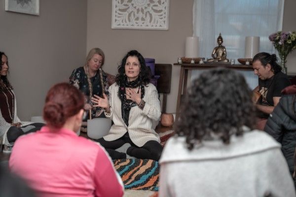 Donna Lakes seated on the floor teaching a circle of Reiki students in the studio